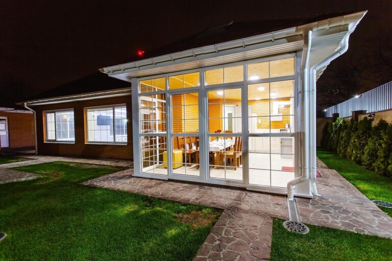 Prachtige tuinoverkapping met transparante dakconstructie, comfortabele zithoeken en warm licht voor optimaal buitencomfort